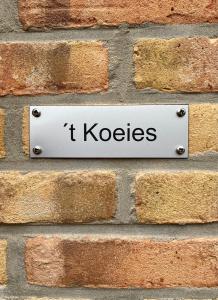 a sign on a brick wall that says t koocses at De Vrije wil in Buren