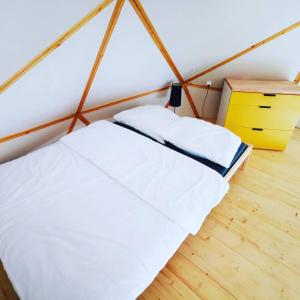 sypialnia z białym łóżkiem i żółtą komodą w obiekcie Nad Narvią - Glamp w Serocku