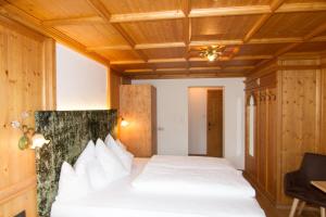a bedroom with a white bed with a wooden ceiling at Haus am Sonnenhang in Finkenberg