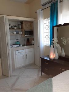 una cocina con armarios blancos y una mesa con flores. en Clarke's Luxurious Private Suite en Spanish Town
