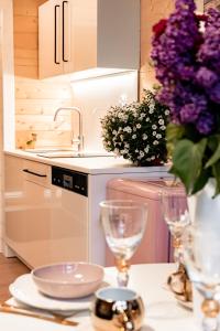 a kitchen with a table with glasses and a vase of purple flowers at Trzy Domki w Mielnie in Mielno