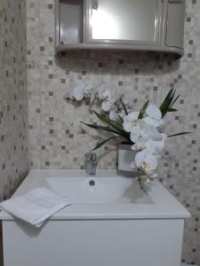 a bathroom sink with a vase of white flowers on it at Clarke's Luxurious Private Suite in Spanish Town