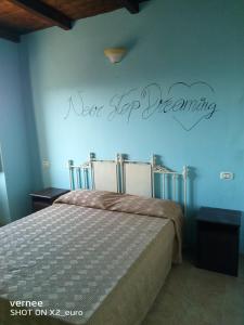- une chambre dotée d'un lit avec les mots « pas à pas » sur le mur dans l'établissement Le Terrazze di Martina, à Nicotera