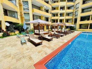 a swimming pool with chairs and umbrellas next to a building at Complex Sands Holiday Apartments in Sunny Beach