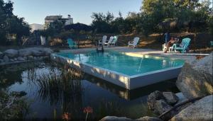 a swimming pool with lawn chairs and chairs around it at Monte das Mariolas in Castelo de Vide