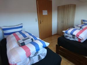 ImmendingenにあるAn der grünen Donau - Ferienwohnung, Monteurwohnung, wir bieten keine Parkplätze, Verpflegung oder Tücher an, Parken NUR gegenüber auf der Straßenseiteのストライプ枕付きのベッド2台が備わる客室です。