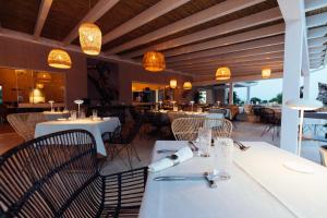 een restaurant met witte tafels, stoelen en verlichting bij Su Entu Sardinian Country Club in Olbia