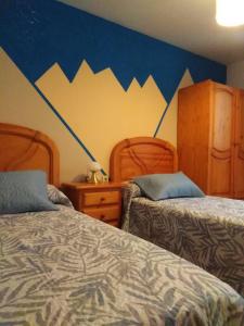 a bedroom with two beds and a wall with mountains at Casa Rural O´LIENO in Oto