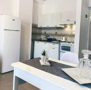 a kitchen with white appliances and a white table at Μaria's flats in Tolo