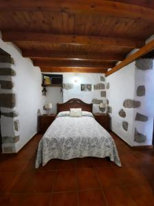 - une chambre avec un lit dans une pièce dotée de murs en pierre dans l'établissement Vv LOS SENDEROS FONTANALES, à Moya