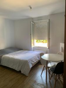 1 dormitorio con cama, mesa y ventana en Résidence les Lilas en Soyaux