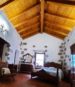 - une chambre avec un lit et un plafond en bois dans l'établissement Vv LOS SENDEROS FONTANALES, à Moya