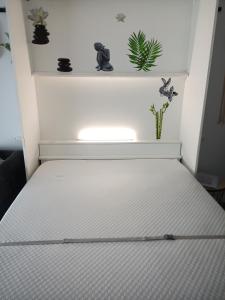 a white bed in a room with plants on a shelf at cosy STUDIO 4 personnes, proche mer et commerce 0 chambre in Le Grau-du-Roi