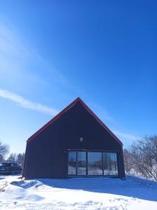 a black building with snow in front of it at Dom na Mazurach z Widokiem Na Las in Jedwabno