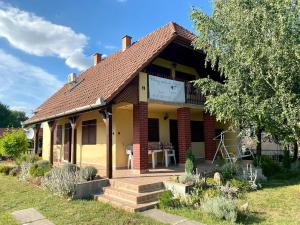 uma pequena casa amarela com um alpendre e escadas em Akácvirág Vendégház em Sarud