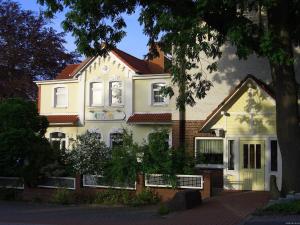 a white house with a tree in front of it at Hotel am Deister in Barsinghausen