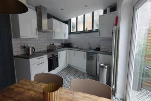 a kitchen with white cabinets and a table with chairs at Shoemakers Cottage in Ramsgate