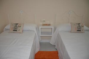 2 camas en una habitación con sábanas y almohadas blancas en Apartamento Sira en Sanxenxo