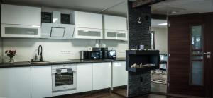 a kitchen with white cabinets and a stove top oven at Golden Beach Apartment in Chlʼaba