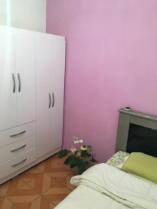 Quarto INDIVIDUAL Casa Super Aconchegante WIFI 350 MEGA في أوساسكو: غرفة نوم بجدران وردية وسرير وخزانة