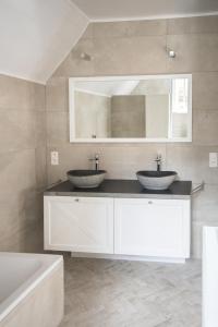 een badkamer met 2 wastafels, een bad en een spiegel bij Tilia in Damme