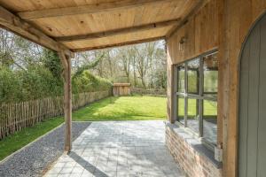 une terrasse couverte ouverte d'une maison avec un toit en bois dans l'établissement Tilia, à Damme