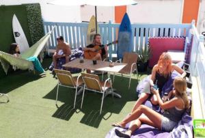 um grupo de pessoas sentadas em torno de uma mesa tocando guitarra em Pura Vida Las Palmas em Las Palmas de Gran Canaria