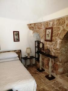 sypialnia z łóżkiem i kamienną ścianą w obiekcie Il Trullo del Cadetto w mieście Francavilla Fontana