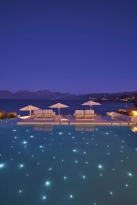 a swimming pool with chairs and umbrellas at night at The Island Concept Luxury Boutique Hotel Heated Pool in Agios Nikolaos