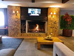 a living room with a stone fireplace with a tv at Alpenhaus Gramado Flat Temporada in Gramado