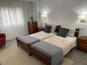 1 Schlafzimmer mit 2 Betten und einem roten Stuhl in der Unterkunft Apartamento Padron Centro P8 by URent in Padrón