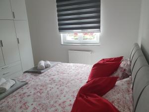 a bedroom with a bed with red sheets and a window at Apartmani Fenestra -Zagorka in Otočac