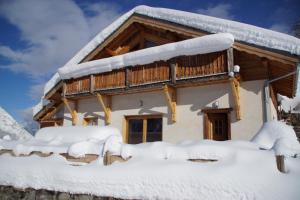 um chalé de madeira na neve com uma varanda em Chalet Le Peak em Valloire