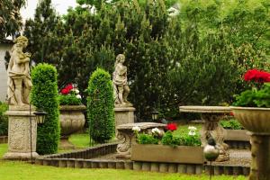 two statues in a garden with flowers and plants at Hotel Alte Post Garni in Ginsheim-Gustavsburg