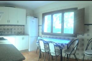 eine Küche mit einem Tisch und Stühlen sowie einem Fenster in der Unterkunft Vivienda vacacional Los Nogales in Llanes