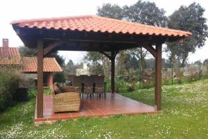 a wooden gazebo with a table and chairs under it at Vivienda vacacional Los Nogales in Llanes