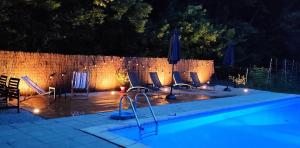 una piscina por la noche con sillas y sombrillas en Le Domaine de Villespy, en Villespy