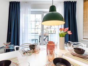 VacationClub – Dubois 16C Apartament 11 في كولوبرزيغ: غرفة طعام مع طاولة مع مصباح أخضر