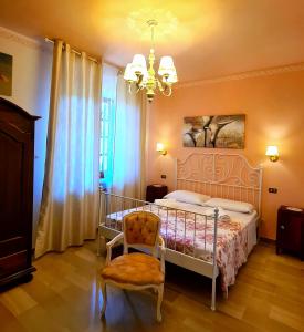 a bedroom with a bed and a chair and a chandelier at b&b Villa Eugenia in Campofilone