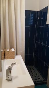 y baño con lavabo y ducha de azulejos azules. en Mango Villa en Les Abymes