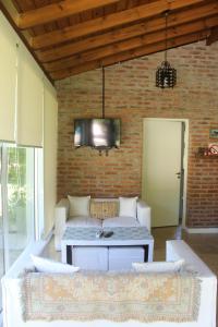 a living room with a couch and a tv on a brick wall at Paraiso Encontrado in Benavídez
