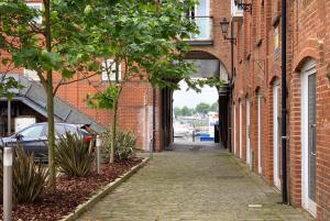 un callejón entre dos edificios de ladrillo con un coche aparcado en The Marina Penthouse, en Ipswich