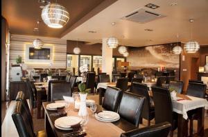 a dining room with tables and chairs and chandeliers at Apartamenty Planeta Mielno in Mielno