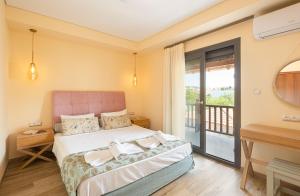 um quarto com uma cama e uma varanda em Regos Resort Hotel em Neos Marmaras