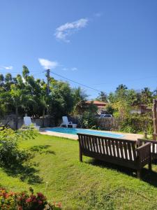 a wooden bench sitting in the grass next to a swimming pool at Pousada Eolos in Barra Grande