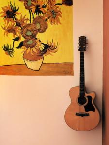 a guitar hanging on a wall next to a painting at Wheat Youth Hostel Qingdao in Qingdao