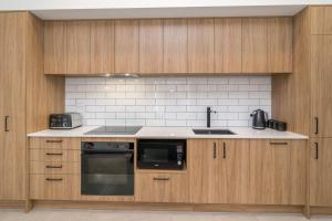 a kitchen with wooden cabinets and a sink and a stove at Inner City Executive Living on Stuart Street in Dunedin