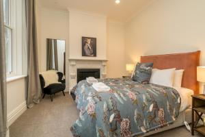 a bedroom with a bed and a chair and a fireplace at Inner City Executive Living on Stuart Street in Dunedin