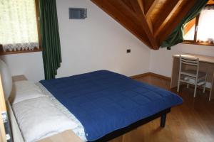 a bedroom with a blue bed and a table at Casa Costa del Sol in Molveno