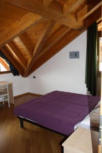 a large purple bed in a room with wooden ceilings at Casa Costa del Sol in Molveno